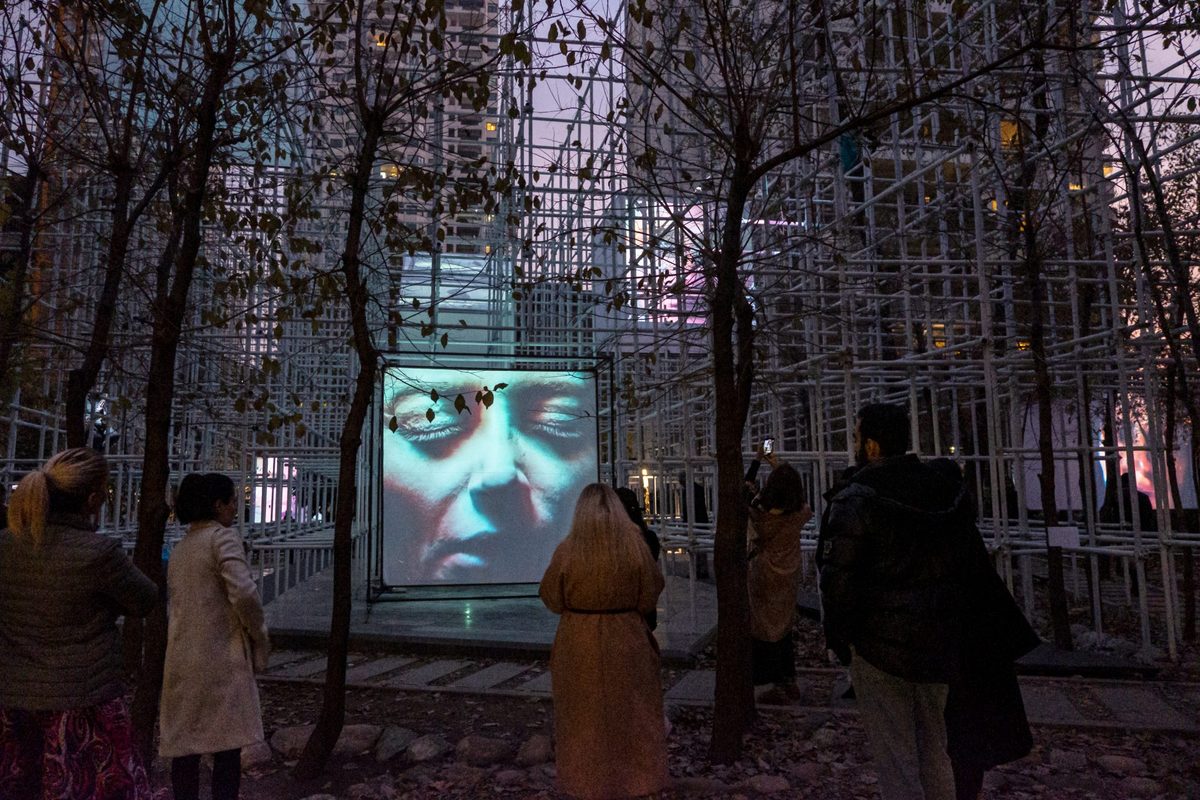 Visitors watching a video work among the trees at Rischee29 Openair Gallery